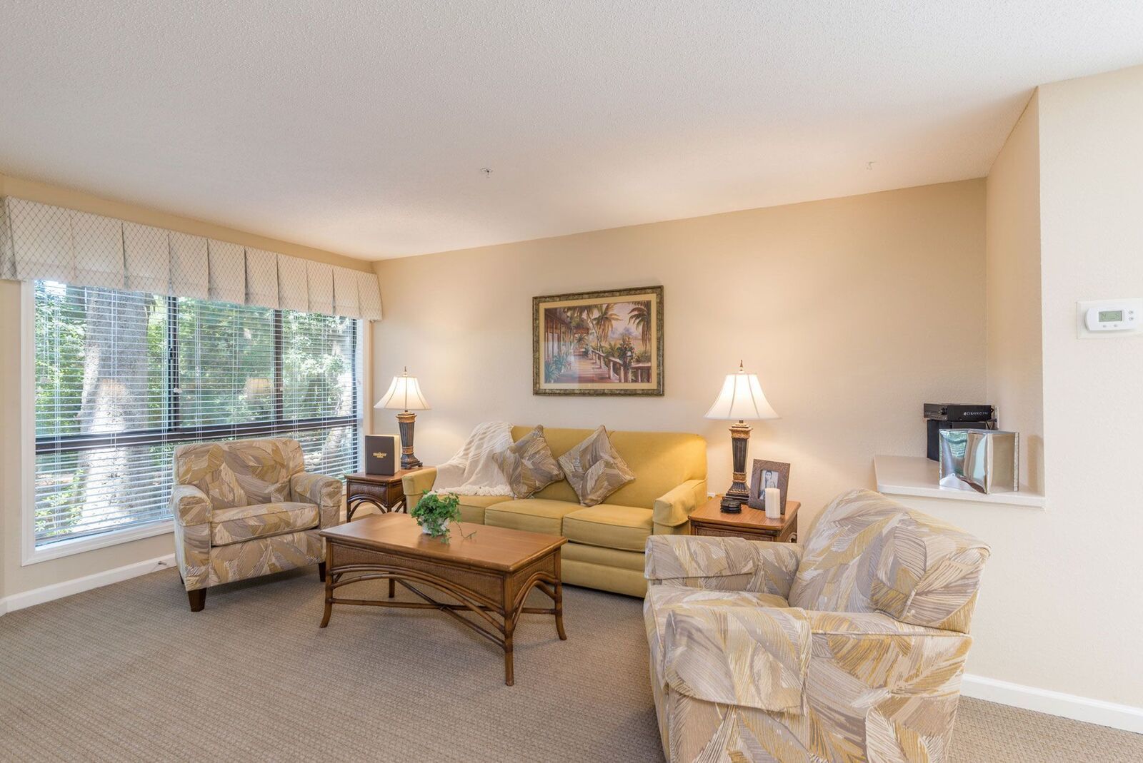 A living room with a sofa, two armchairs, a coffee table, and a painting on the wall.