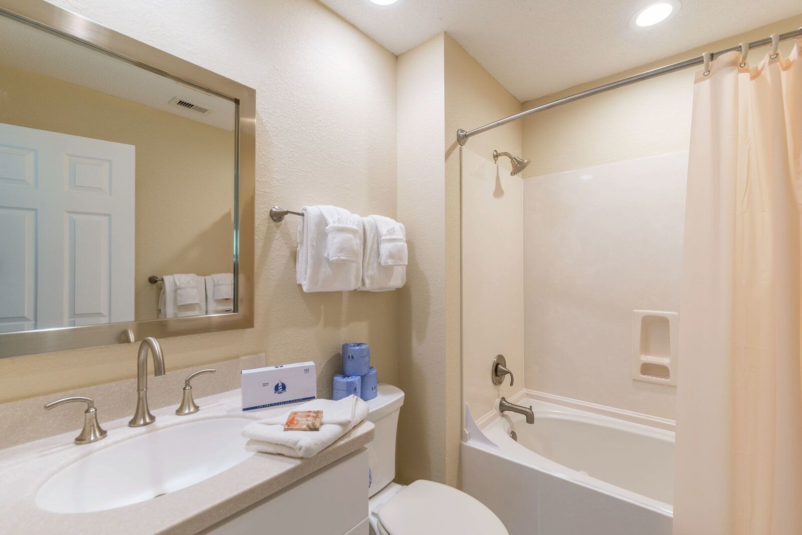 A bathroom with a double sink, a toilet, a bathtub, and a shower curtain.
