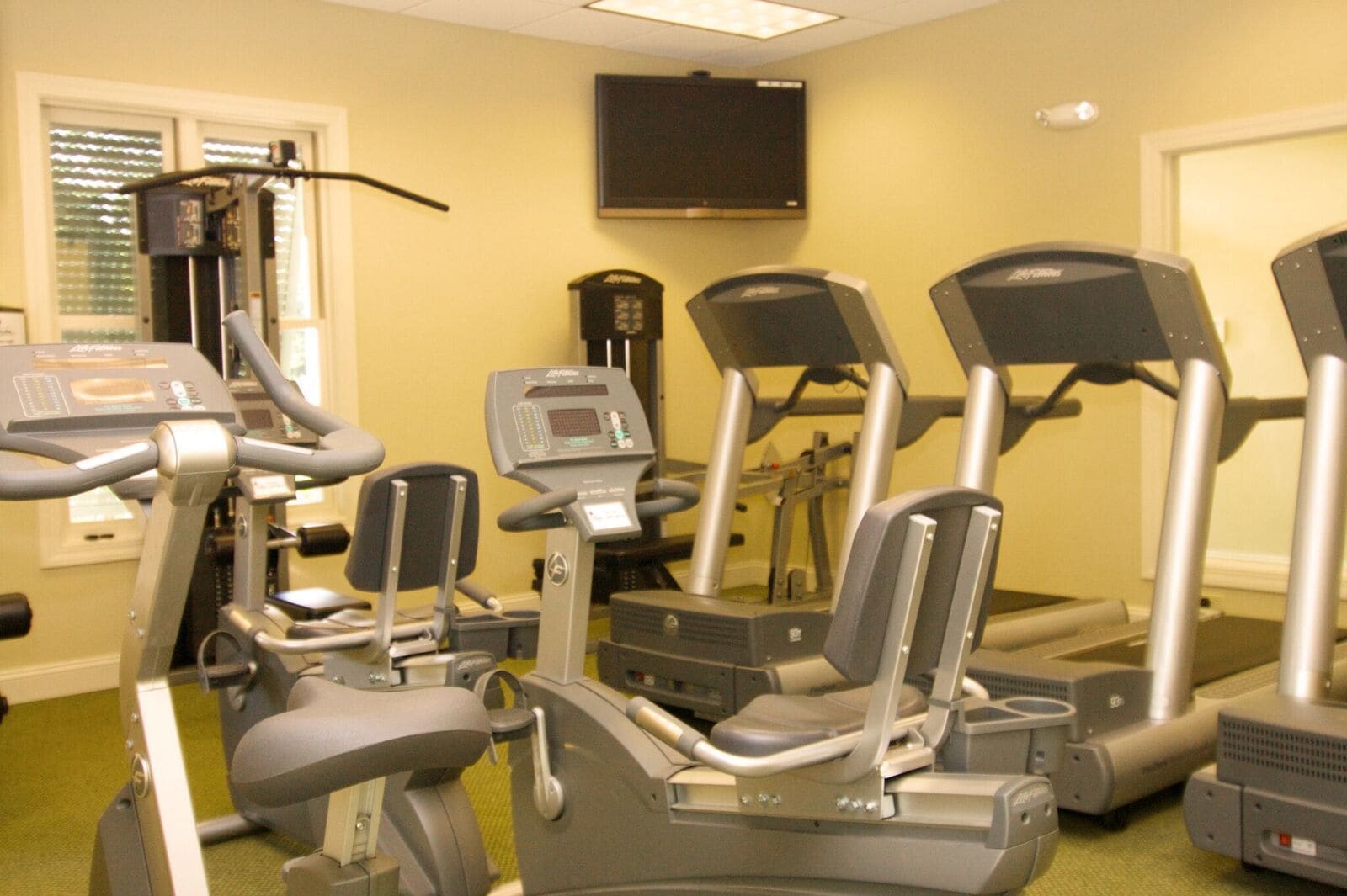 Una palestra attrezzata con tapis roulant, ellittiche e una cyclette.