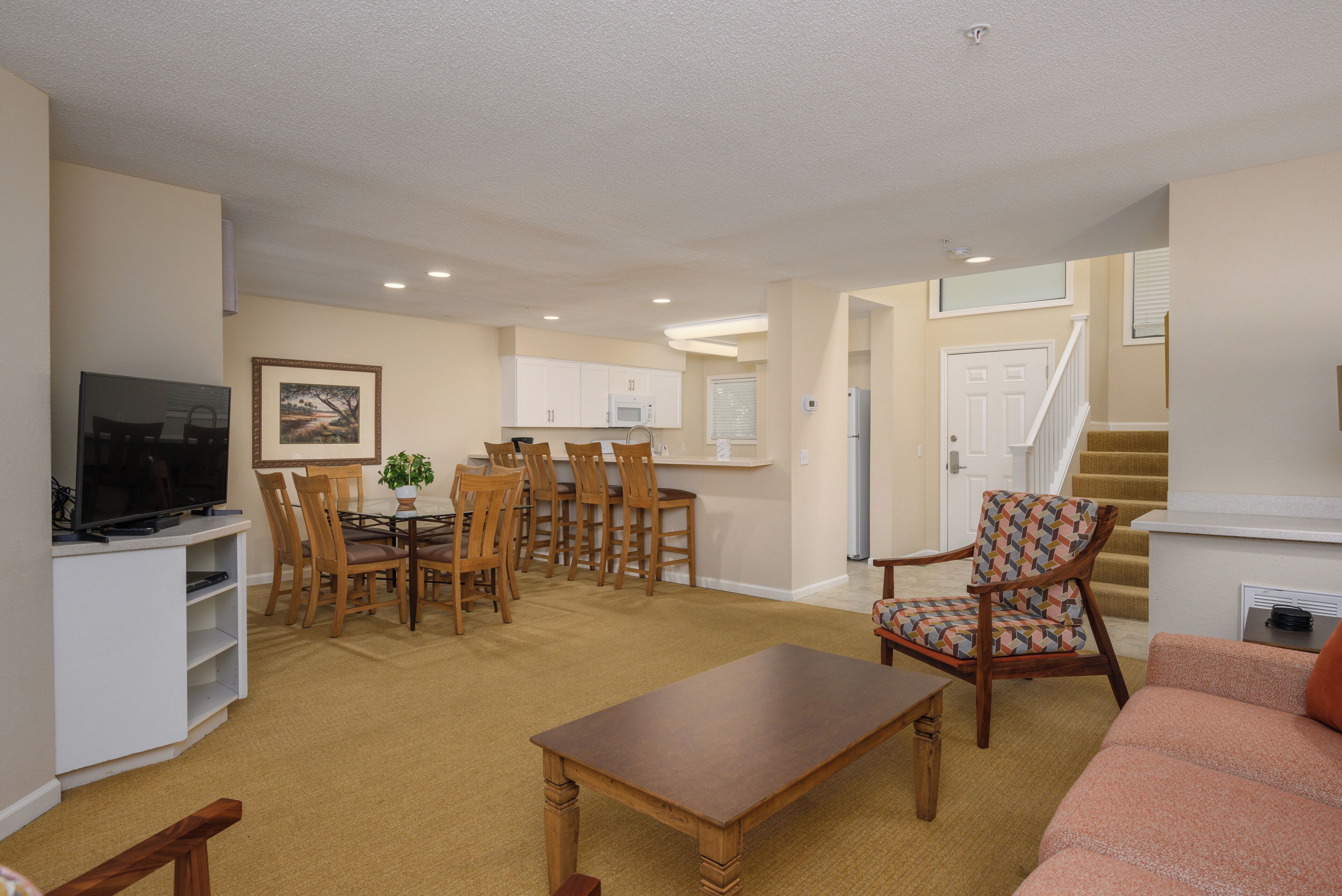 A living room with a TV, dining table, chairs, and a sofa.