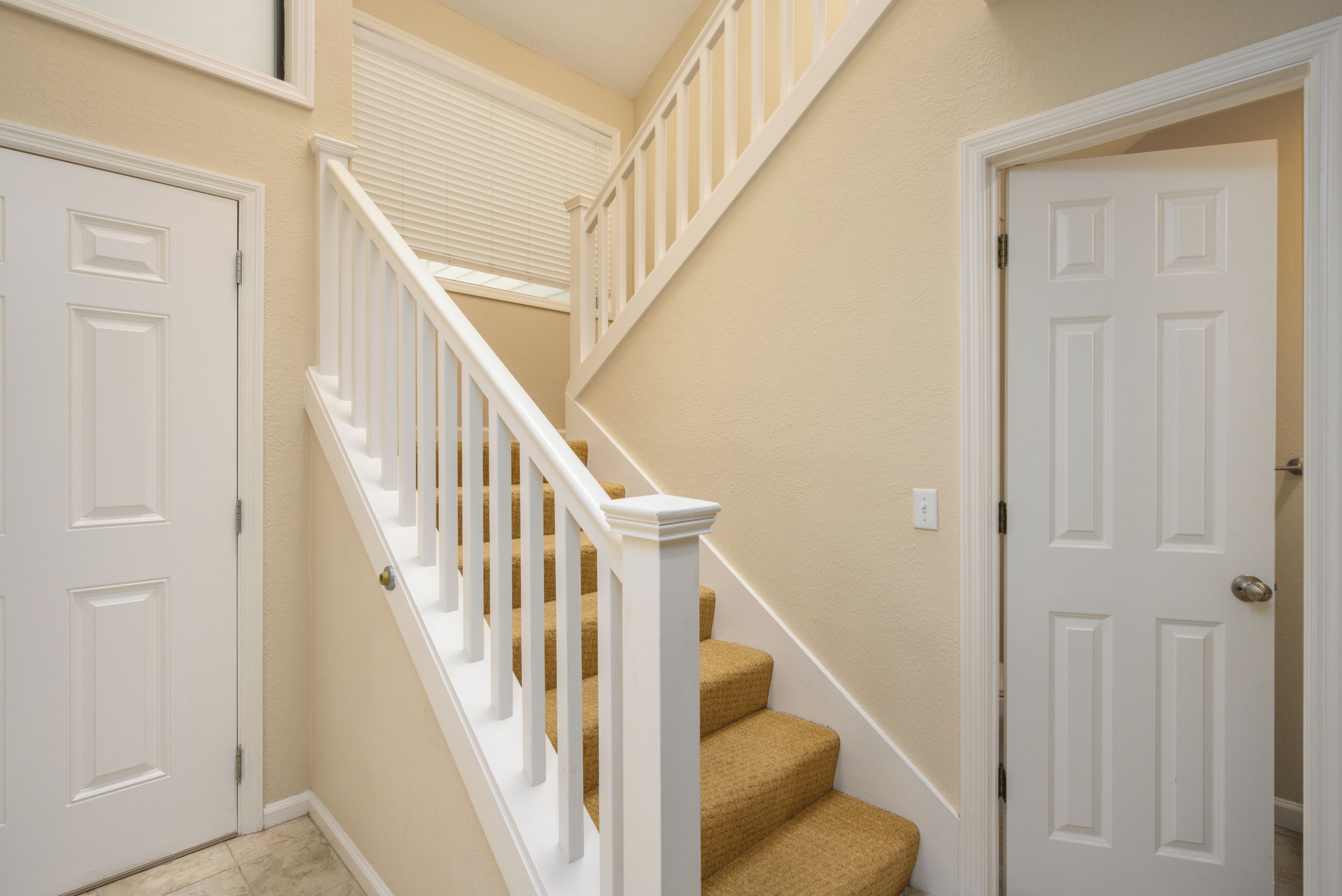 A staircase with white railings and carpeted steps leading to a landing.