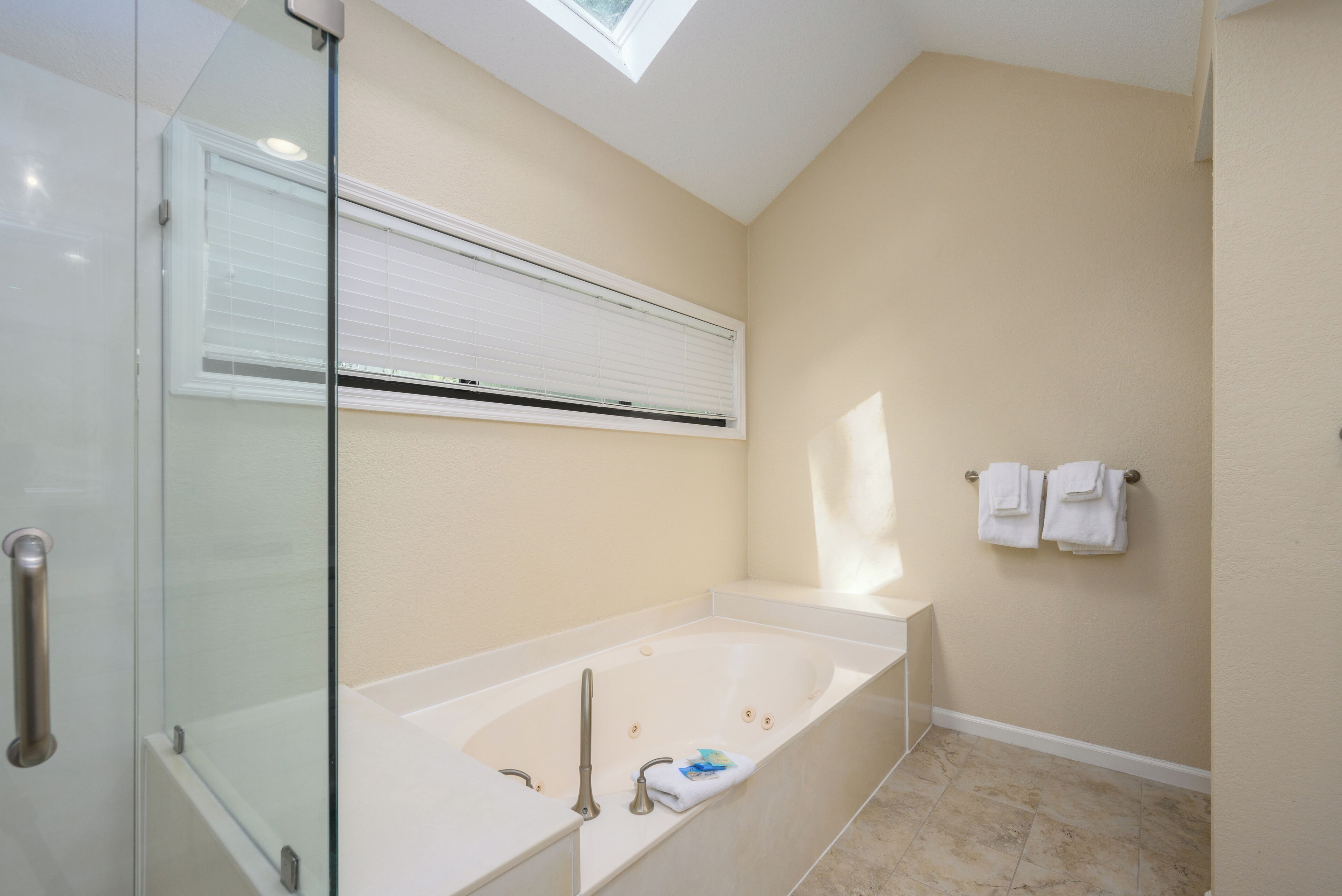 Un baño moderno con cabina de ducha de vidrio, bañera independiente y un perchero en la pared.