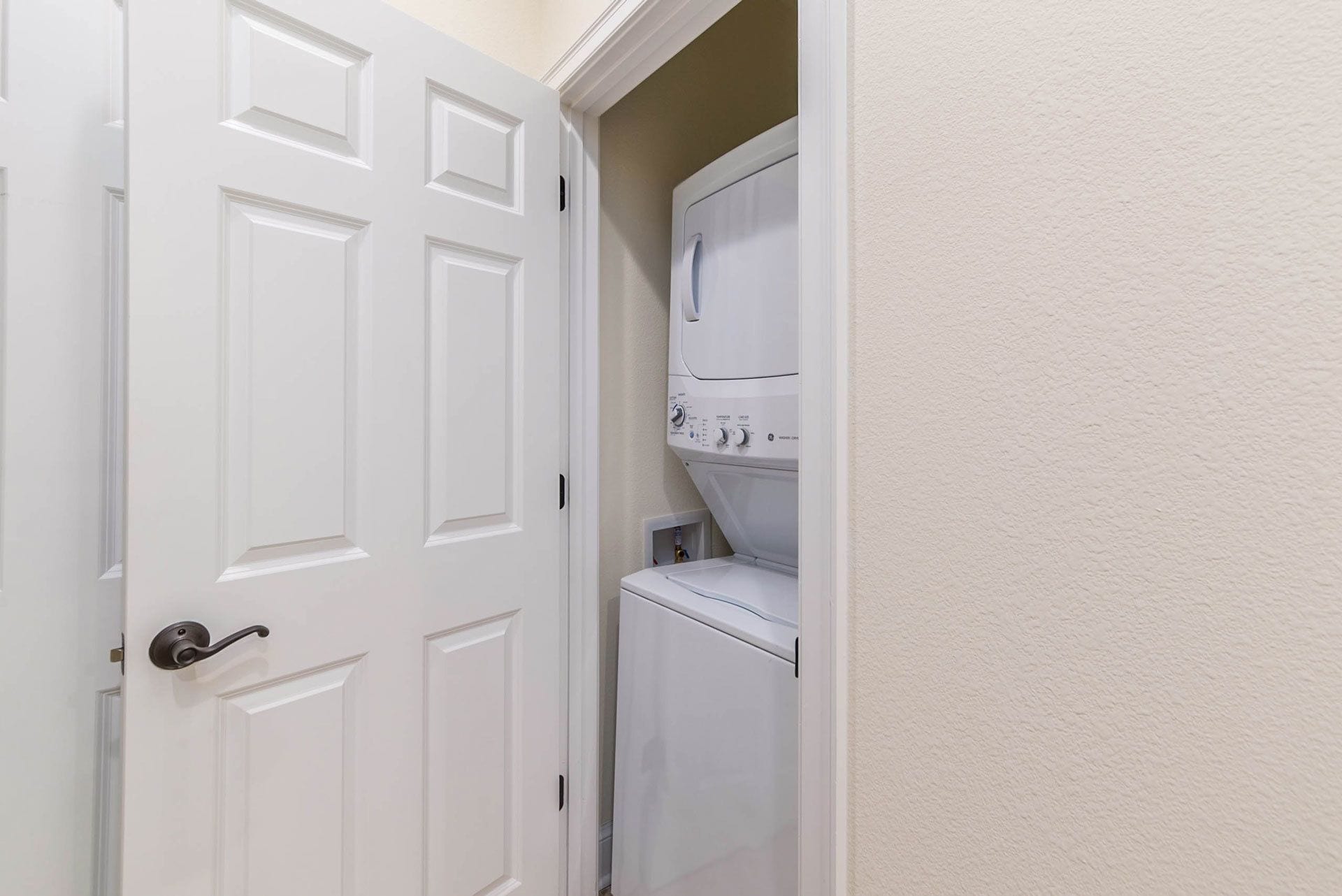 A laundry room with a white door and stacked washer and dryer.