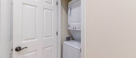 A laundry room with a white door and stacked washer and dryer.