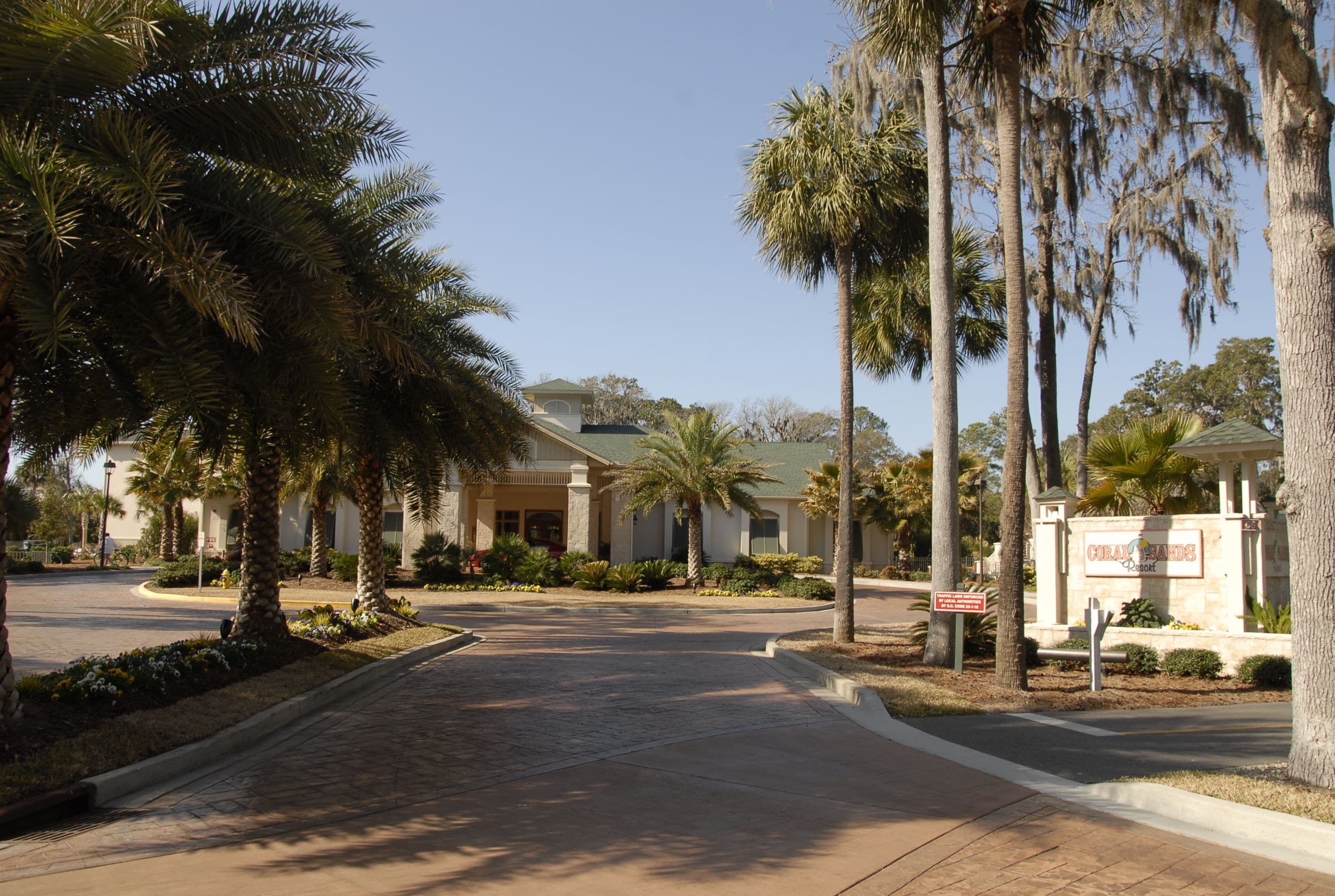 A residential street with palm trees, a house with a green roof, and a sign for Coral Ridge.