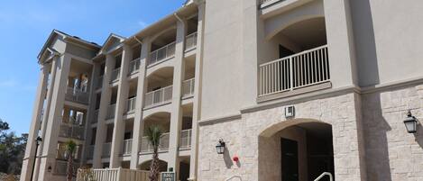A multi-story building with balconies, a stone facade, and a gated entrance.