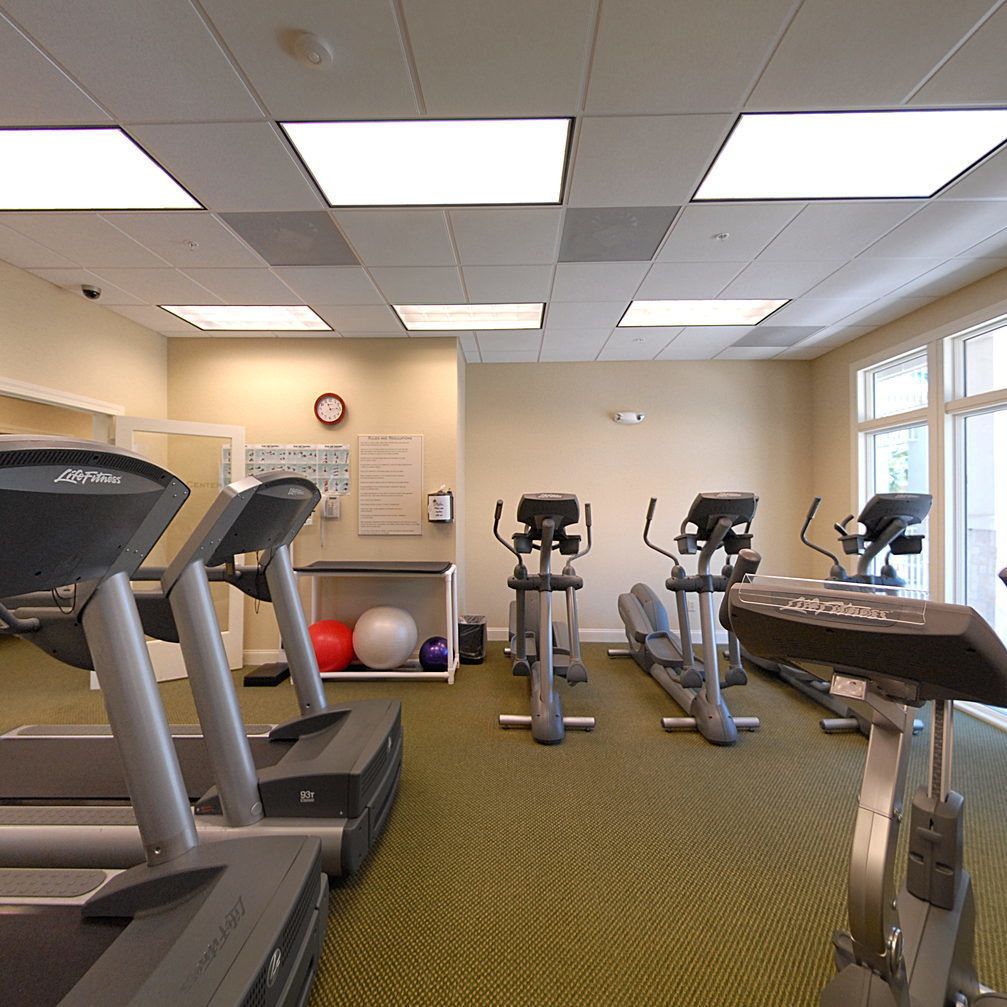 Ein Fitnessstudio mit Laufbändern, Crosstrainern und Fitbällen.