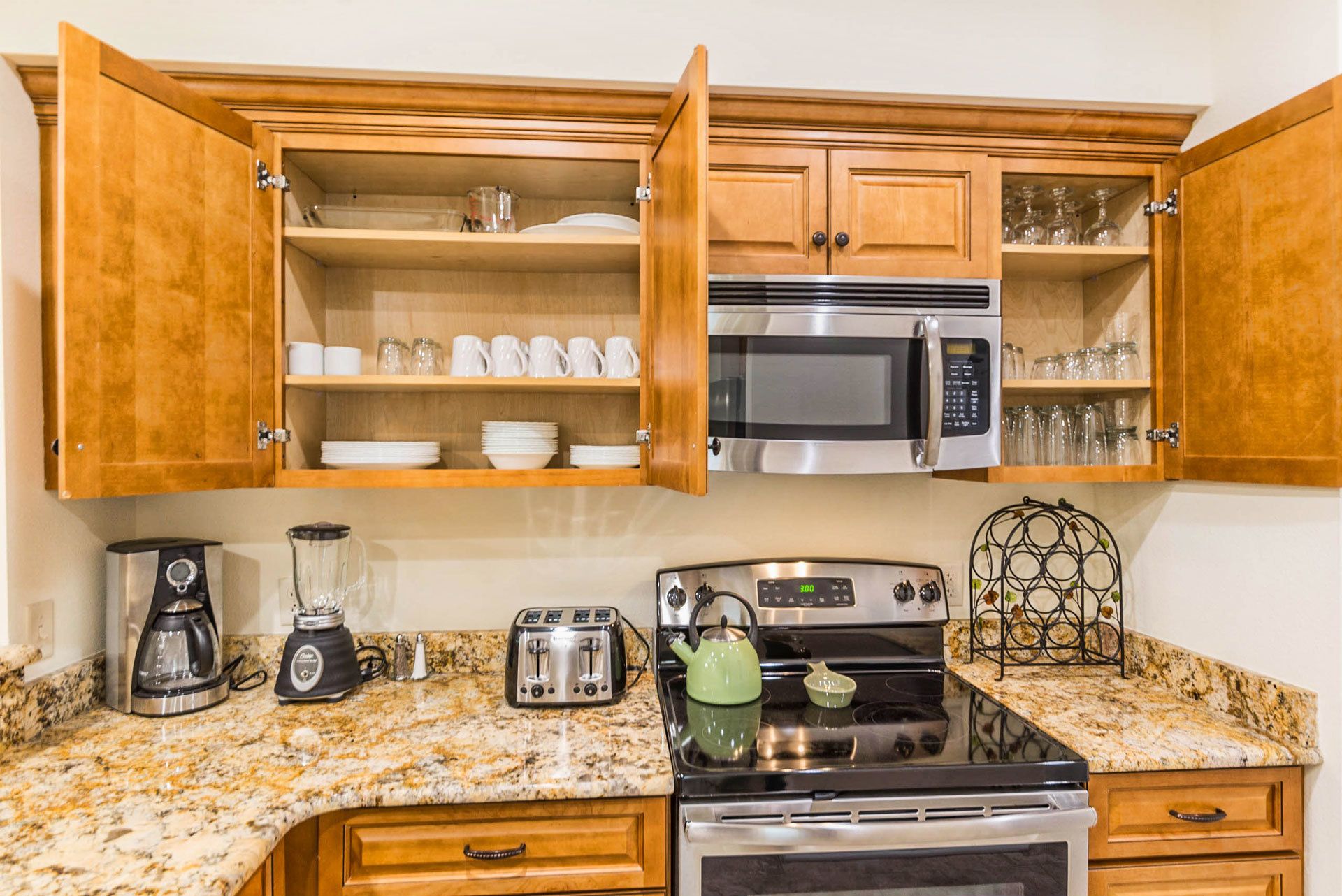 A kitchen with wooden cabinets, a microwave, a stove, a coffee maker, and a toaster.
