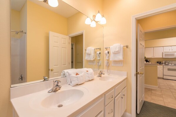 A bathroom with a double sink, a large mirror, and a hairdryer.