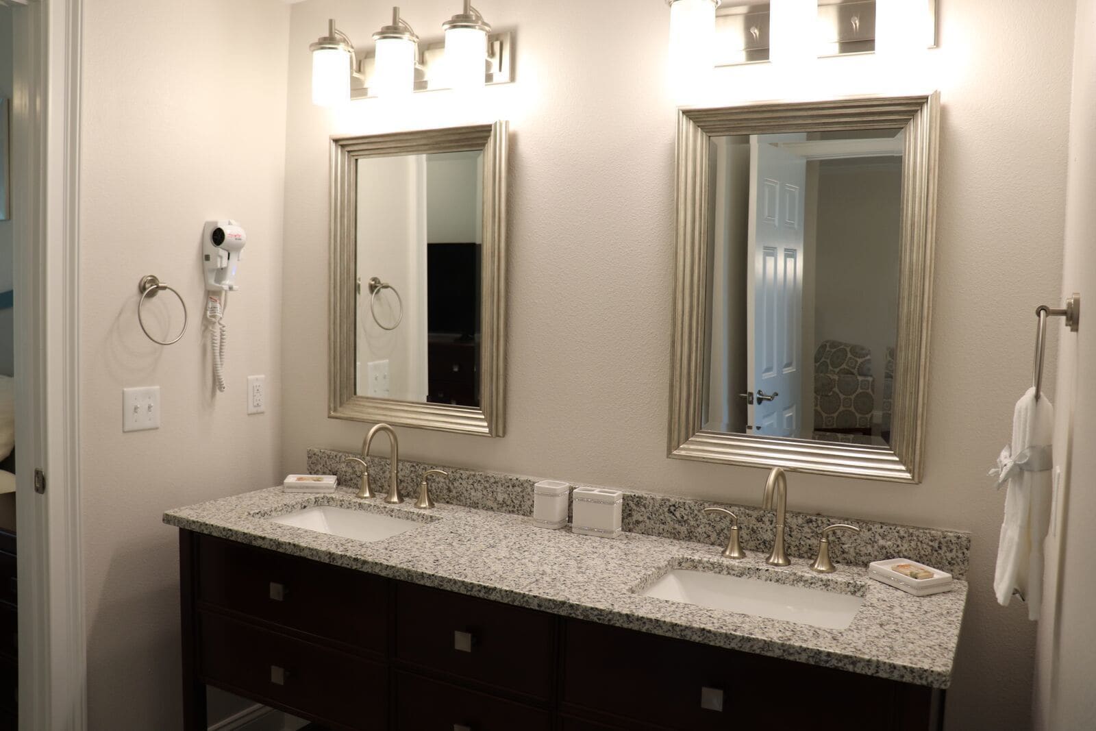 A bathroom with two sinks, a large mirror, and a hairdryer on the wall.