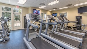 Une salle de sport équipée de tapis de course, de vélos d’exercice et d’appareils de musculation.