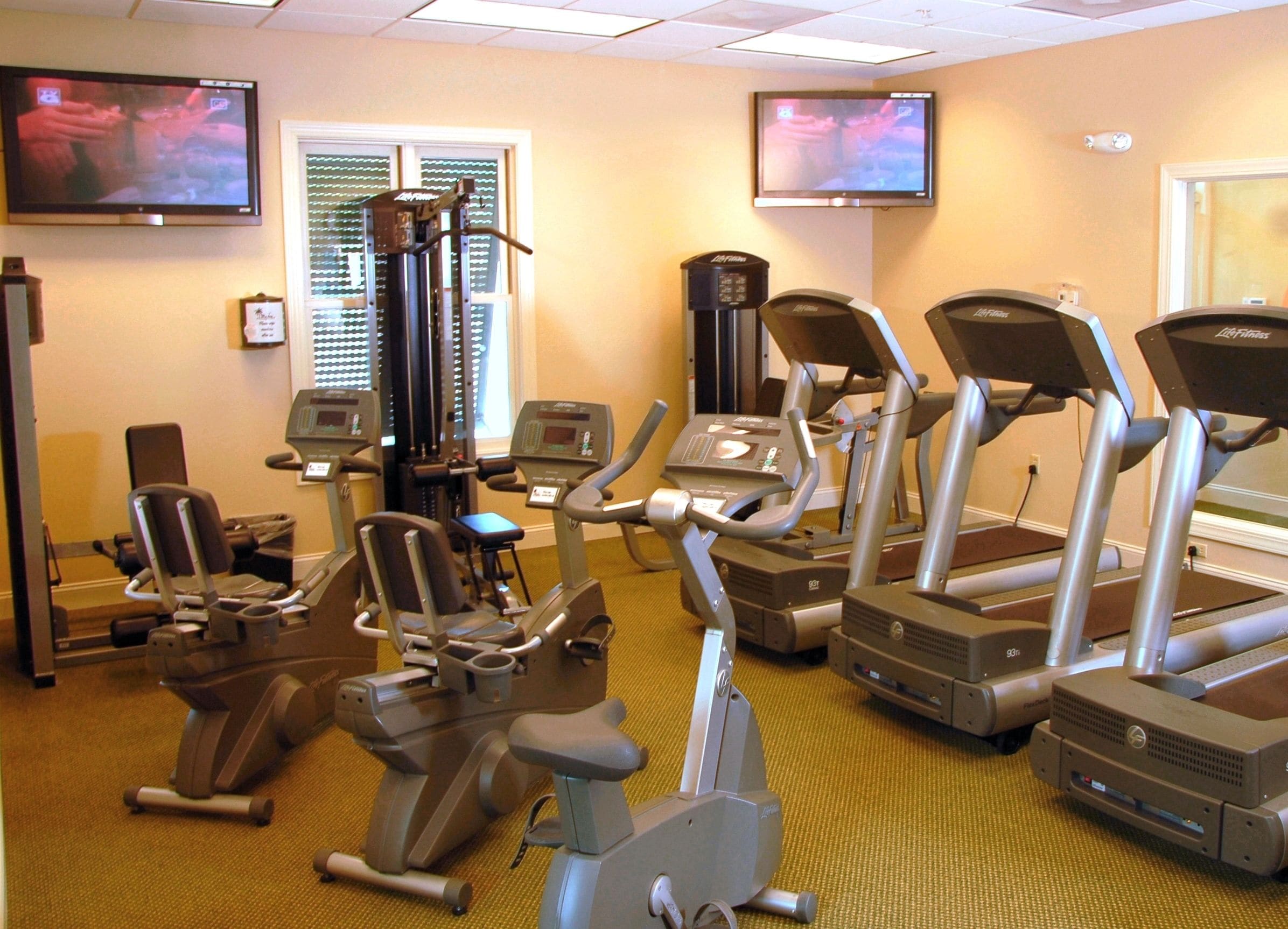 Een fitnessruimte met loopbanden, elliptische trainers en krachtapparaten.