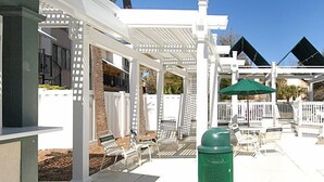 Un espace extérieur abrité, doté de structures blanches, notamment une pergola et des sièges.