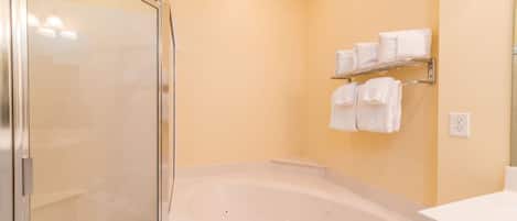 Een moderne badkamer met een douchecabine van glas, een vrijstaand bad en een handdoekrek met meerdere handdoeken.