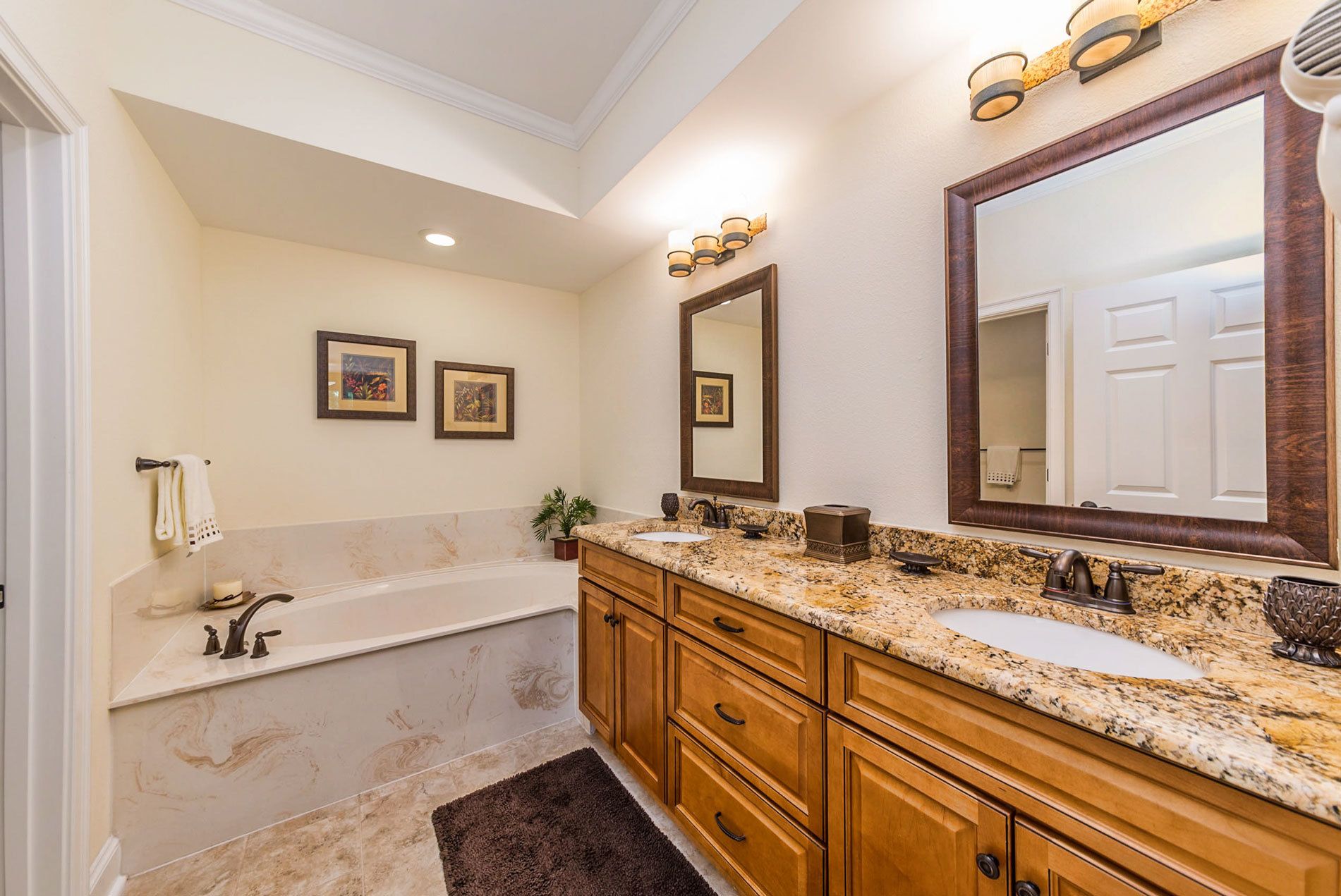 Une salle de bain avec une baignoire, un lavabo et un grand miroir. On y trouve des meubles en bois et un comptoir en marbre.