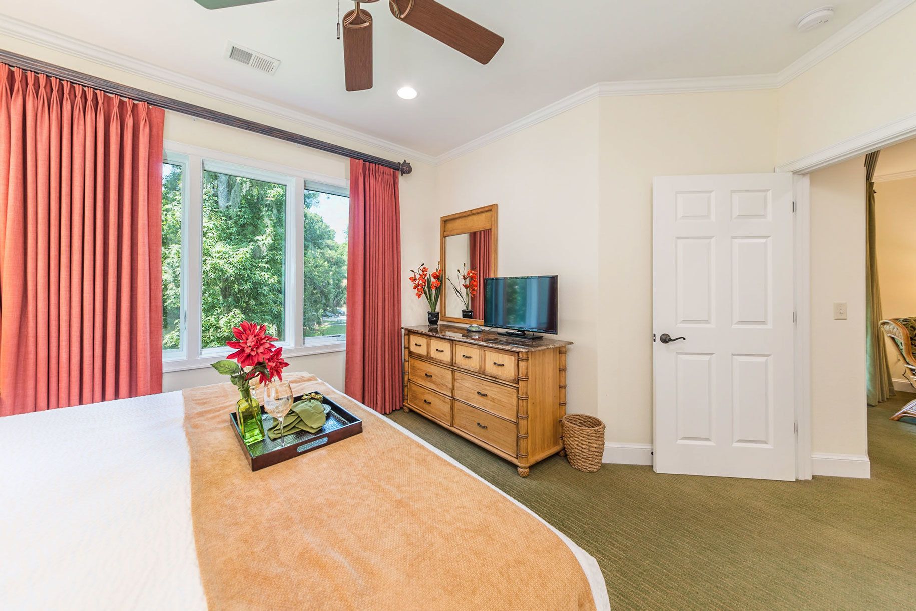 A hotel room with a bed, a wooden dresser, a television, and a window with curtains.
