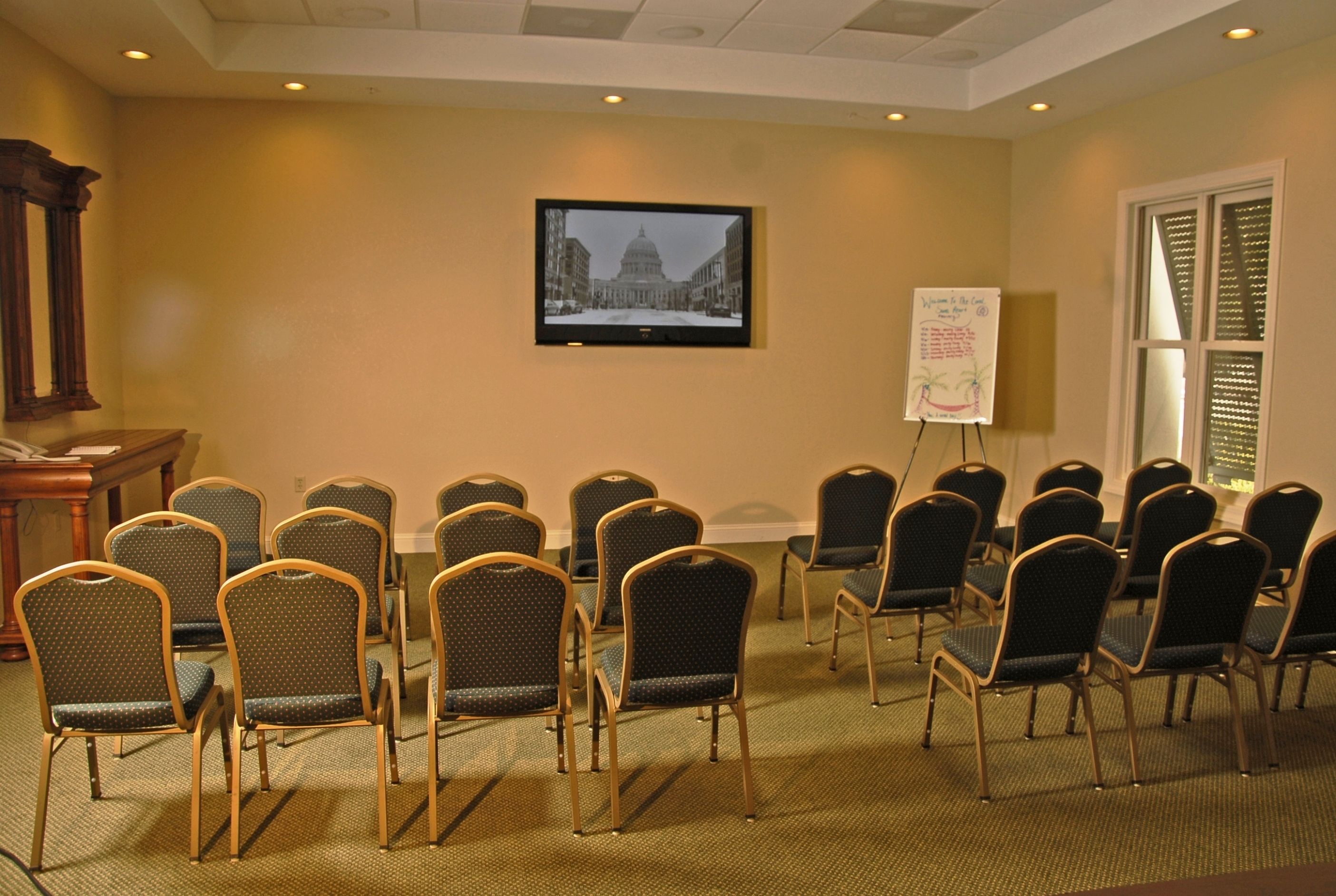 A conference room with rows of chairs, a television on the wall, and a whiteboard.