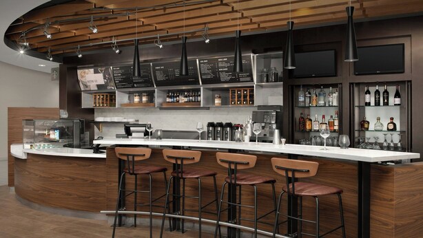 A modern bar area with a curved counter, bar stools, and a menu board. - Residence Inn by Marriott Syracuse Downtown at Armory Square (Syracuse)