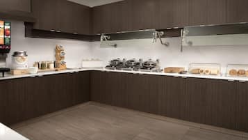 A modern kitchen with dark wood cabinets, white countertops, and stainless steel appliances.