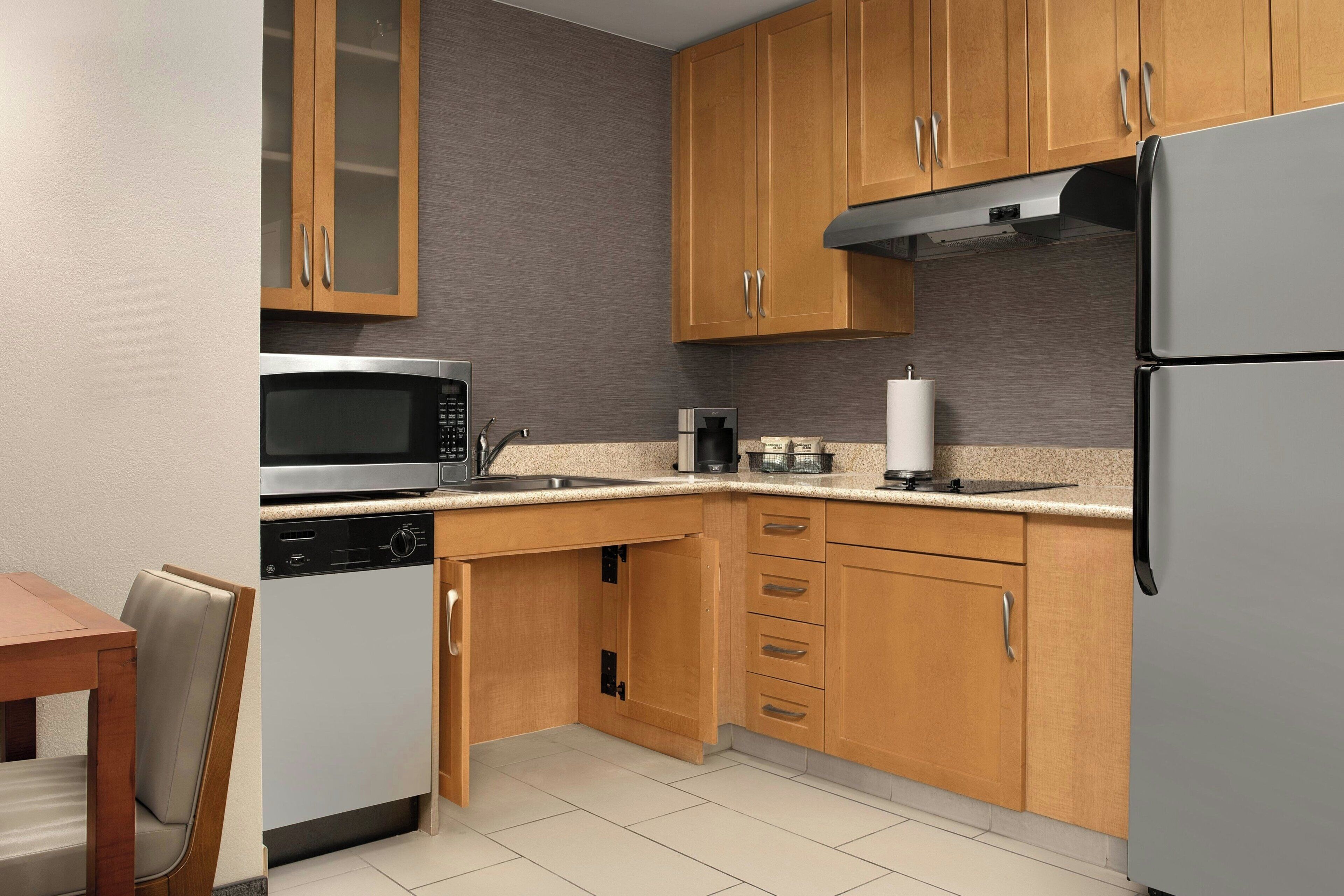 A kitchen with wooden cabinets, a stainless steel microwave, a dishwasher, and a refrigerator.