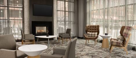 A modern lounge area with leather chairs, a fireplace, and large windows offering city views.