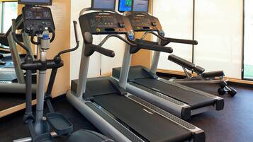 Três esteiras de corrida com mostradores digitais, uma garrafa de água e uma esteira com pedais.