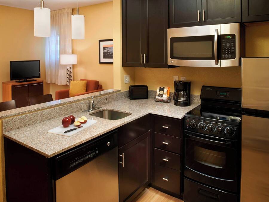 A compact kitchen with a microwave, stove, and dishwasher. There is a small dining area with a table and chairs.