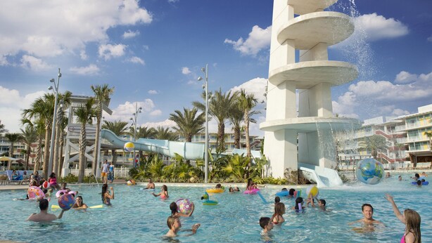 A swimming pool area with multiple water slides and palm trees. - Universal's Cabana Bay Beach Resort (Orlando)