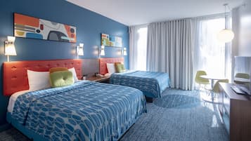A hotel room with two beds, a desk, a chair, and a large window with curtains.