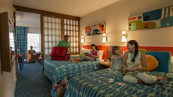 A hotel room with two beds, a sitting area, and a view of the city.