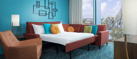 A hotel room with a bed, a sofa, a chair, and a large window with a view.
