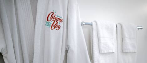 Un baño con toallas blancas y una bata colgada en un perchero.