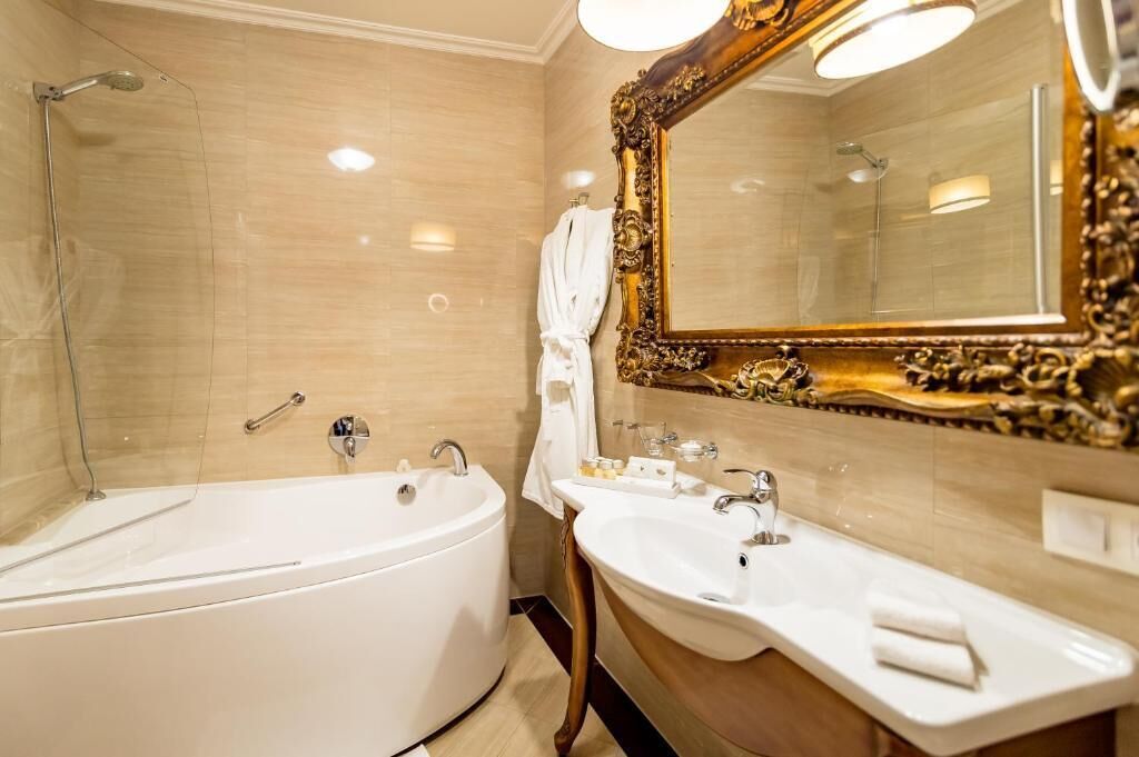 A bathroom with a bathtub, a sink, and a large ornate mirror.