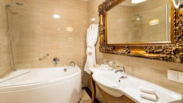 A bathroom with a bathtub, a sink, and a large ornate mirror.