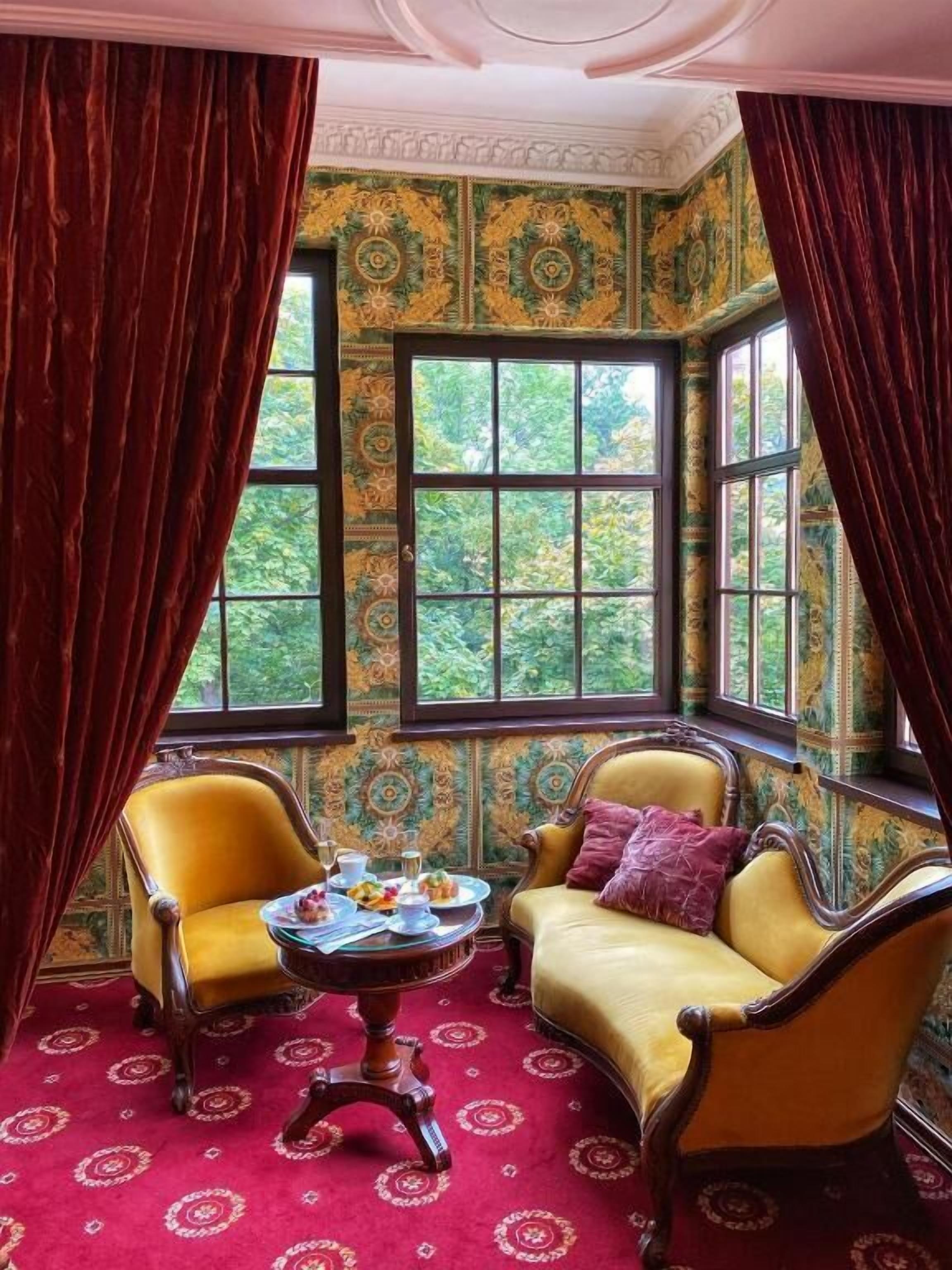 A room with two chairs, a table, and a window with curtains.