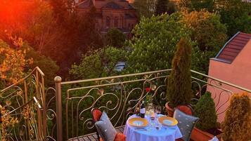 Una terraza con una mesa preparada para dos, con vista a una iglesia y al atardecer.