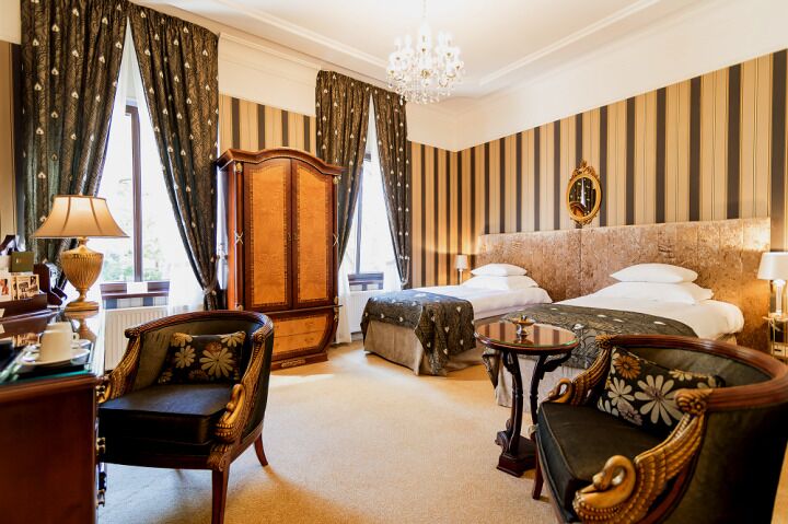 A hotel room with a large bed, two bedside tables, a chair, a desk, and a wardrobe.