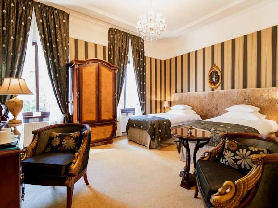 A hotel room with a large bed, two bedside tables, a chair, a desk, and a wardrobe.