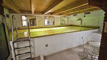 A pool area with a long, narrow pool, a ladder, and a seating area with metal chairs.
