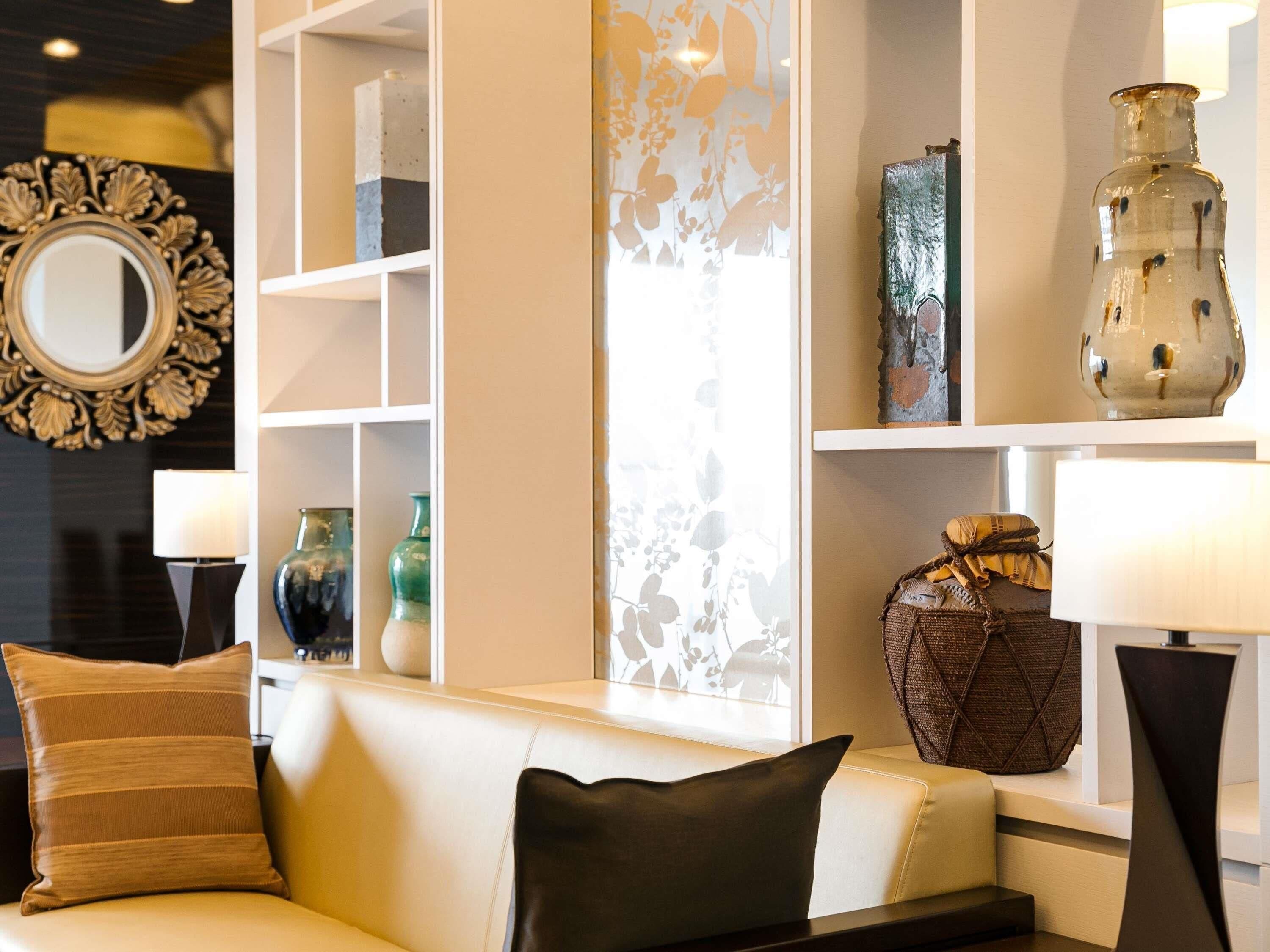 A modern living room with a sofa, decorative vases, and a mirror on the wall.