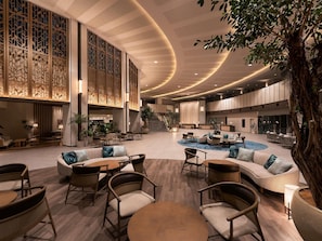 A spacious lobby with a central seating area, a staircase, and a reception desk. - Grand Mercure Okinawa Cape Zanpa Resort (Yomitan)