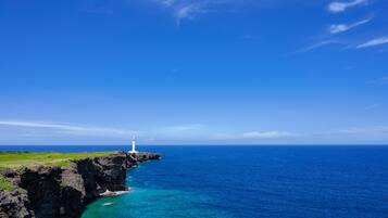 A lighthouse on a rocky cliff overlooking a clear blue sea.