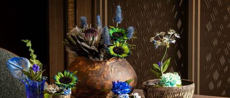A wooden table with various flower arrangements in different containers.