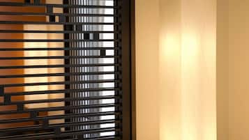 A room with a modern, minimalist design, featuring a black partition with horizontal slats and a tall, narrow wall-mounted light fixture.