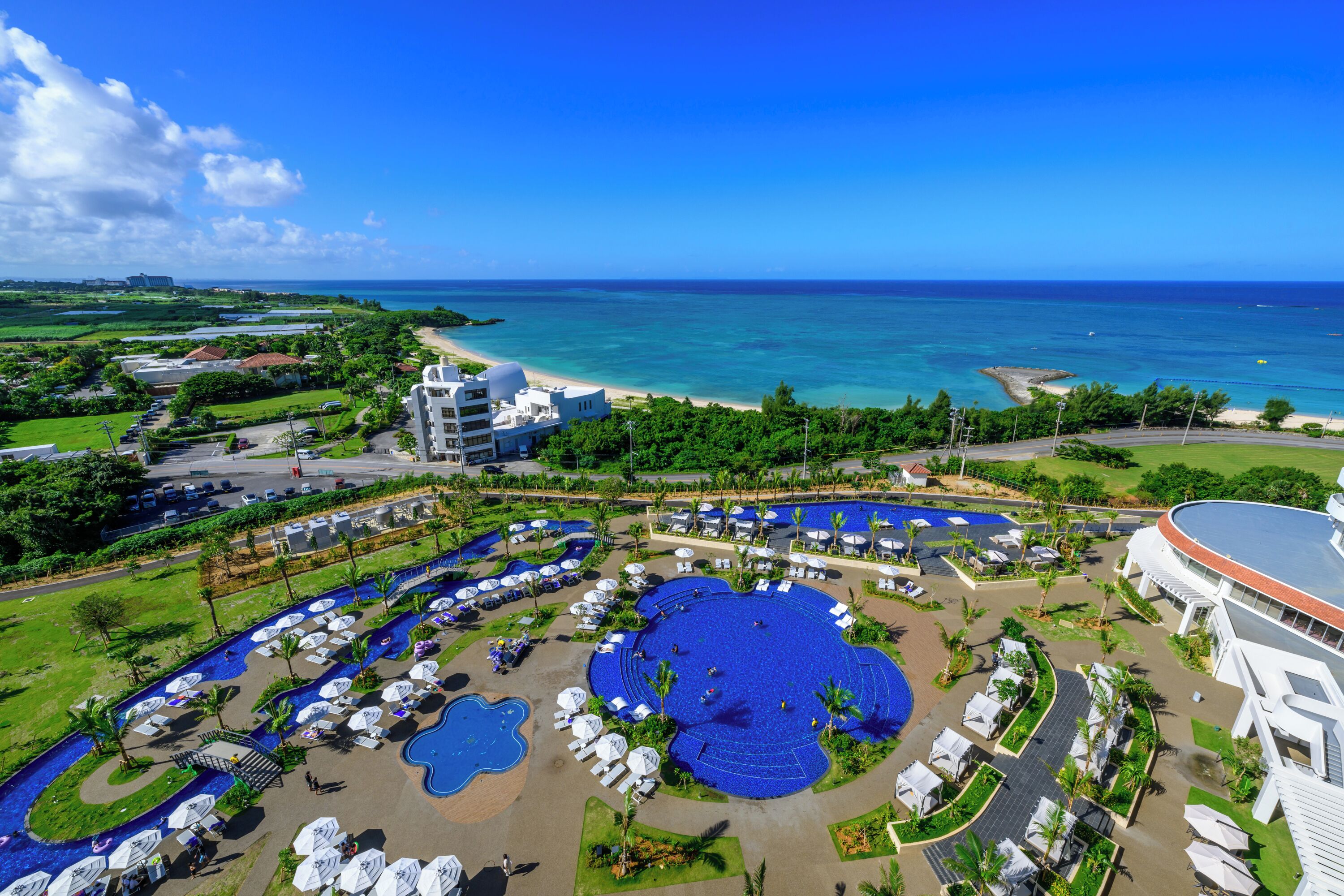 A resort with a large central pool, multiple smaller pools, and a beach area.