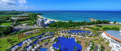 Un resort con una amplia piscina central, varias piscinas más pequeñas y una zona de playa.