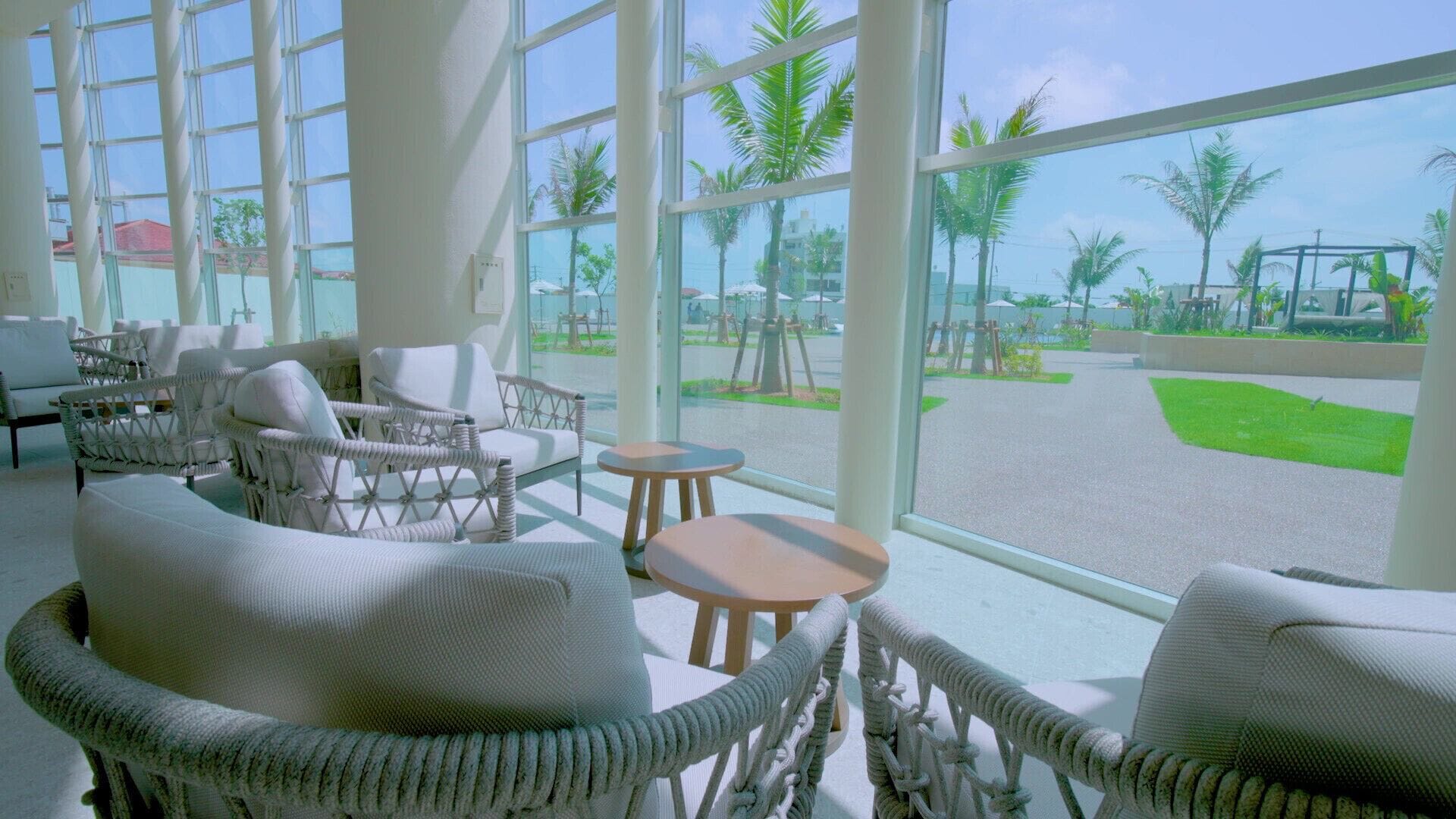 A bright room with wicker furniture, large windows, and a view of a green landscape.