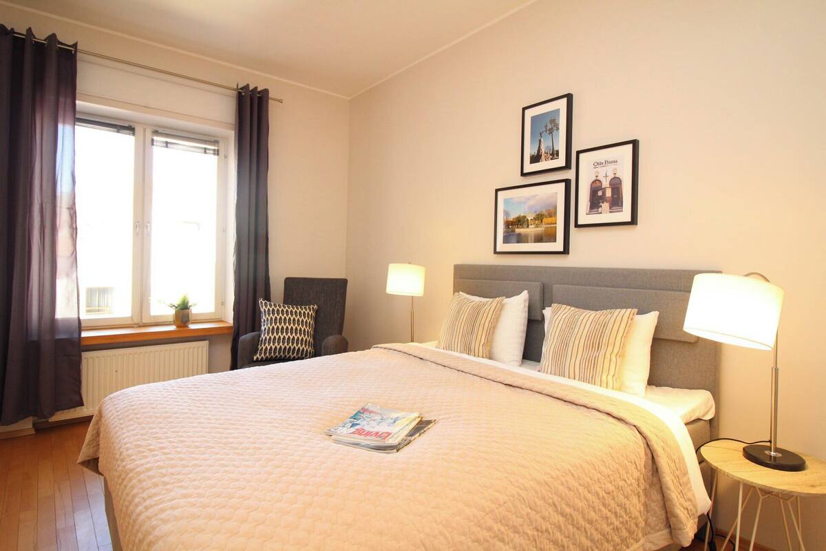 Une chambre d’hôtel bien aménagée, avec un grand lit, deux lampes de chevet, une chaise et une petite table.