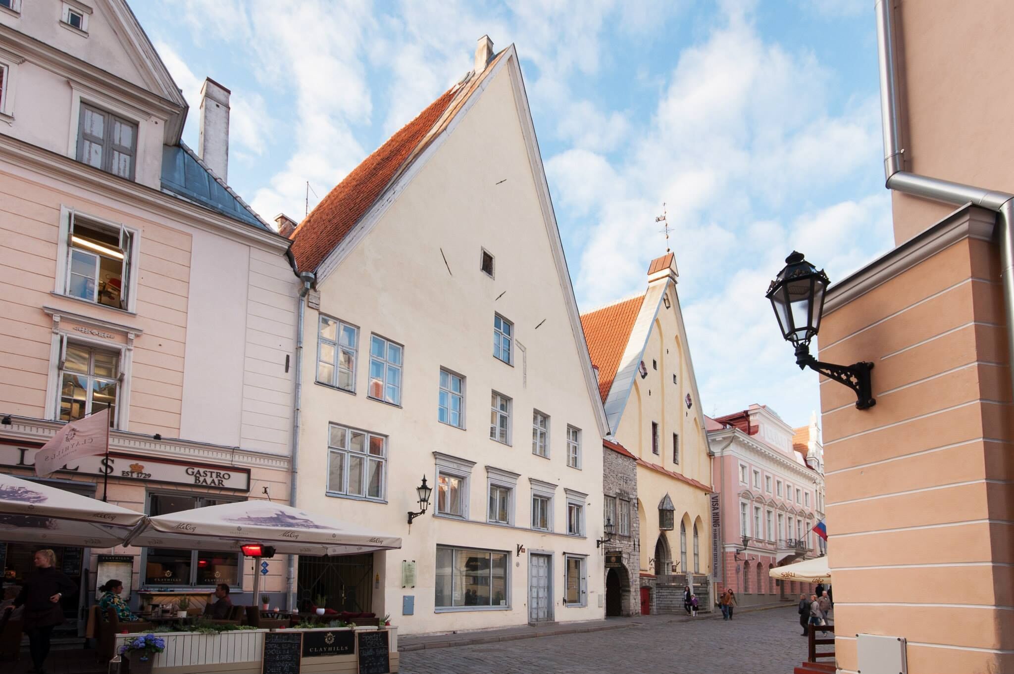 A street with buildings, including a restaurant and a bar, and a cobblestone street.