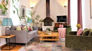 Un salon avec une cheminée, un canapé, un fauteuil, une table basse et un téléviseur.